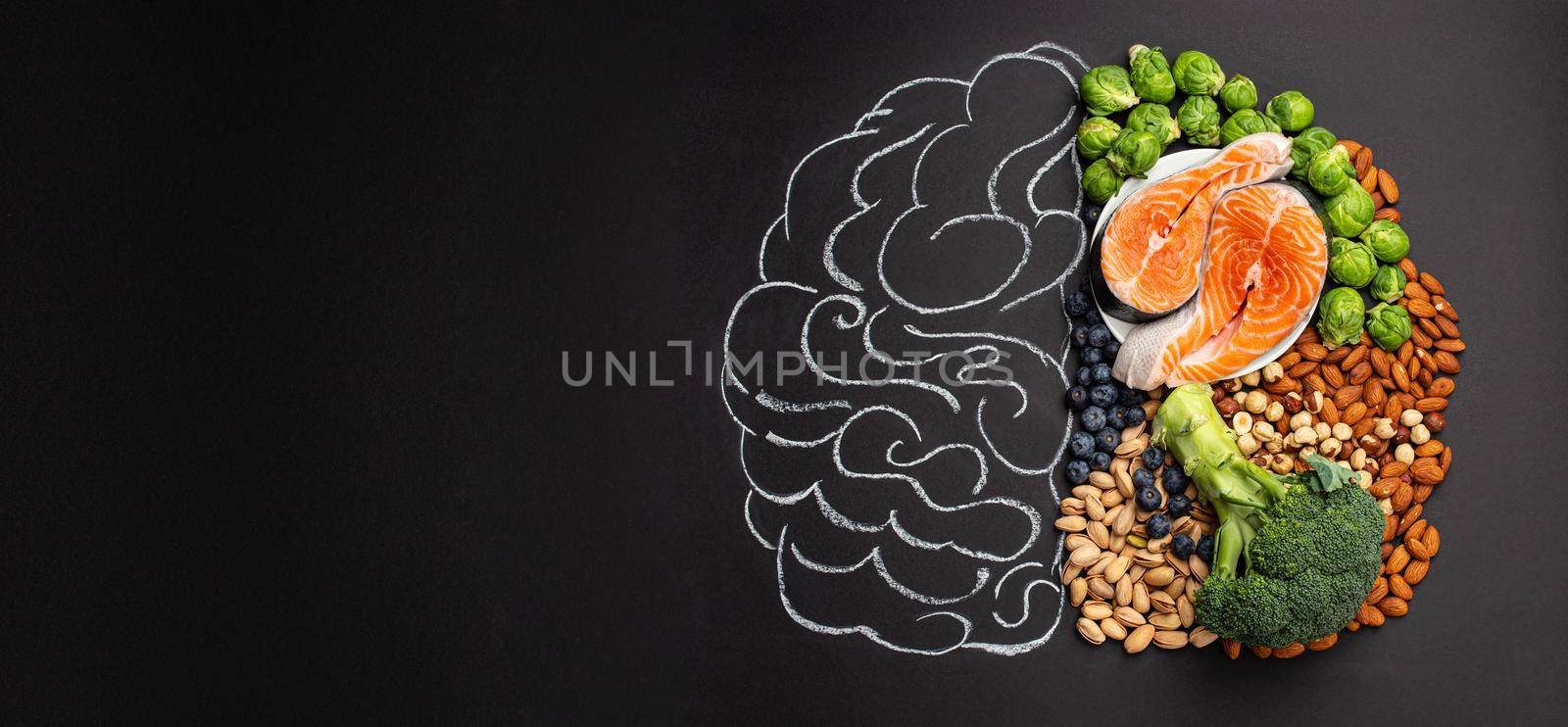 Chalk hand drawn brain picture with assorted food, food for brain health and good memory: fresh salmon, vegetables, nuts, berries on black background. Foods to boost brain power, top view, copy space..