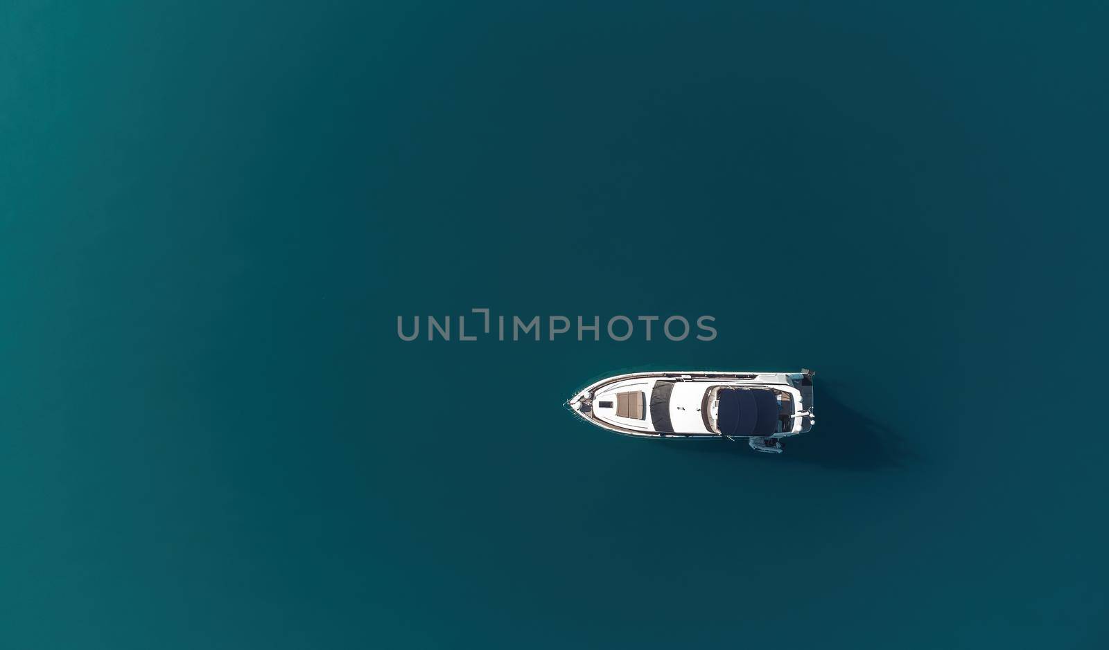 Aerial boat race. Luxury cruise trip. View from above of white boat on deep blue water. Aerial view of rich yacht sailing sea. Motor boat racing wave. Summer journey on luxury ship