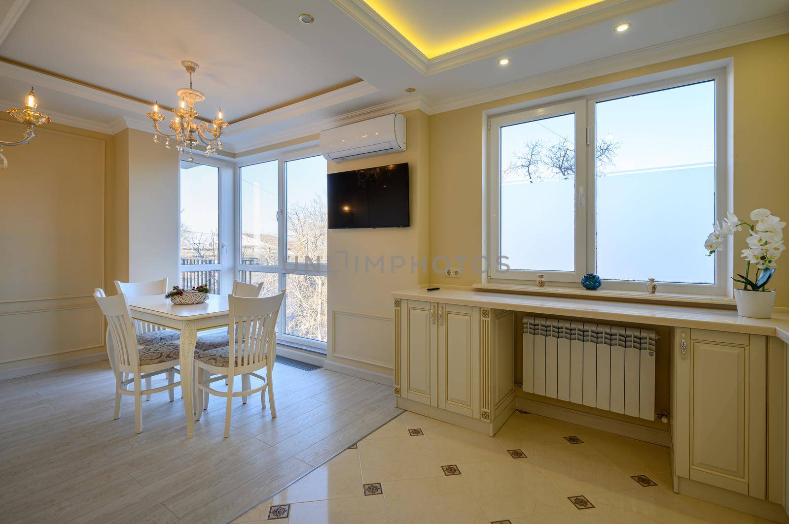 Classic white and beige luxurious kitchen with dining table in studio apartment interior