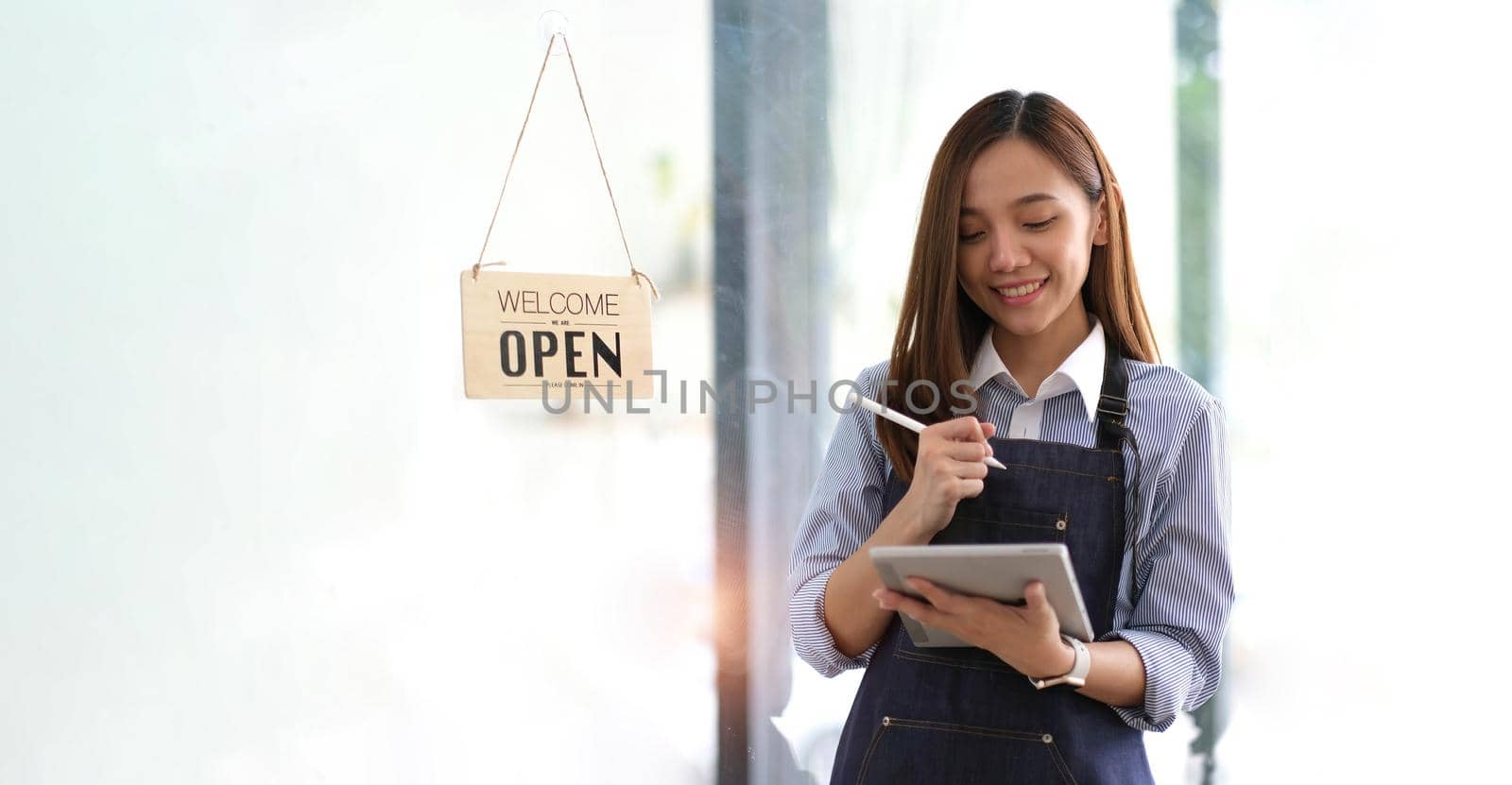 Startup successful small business owner sme beauty girl stand with tablet smartphone in coffee shop restaurant. Portrait of asian tan woman barista cafe owner. SME entrepreneur seller business concept.