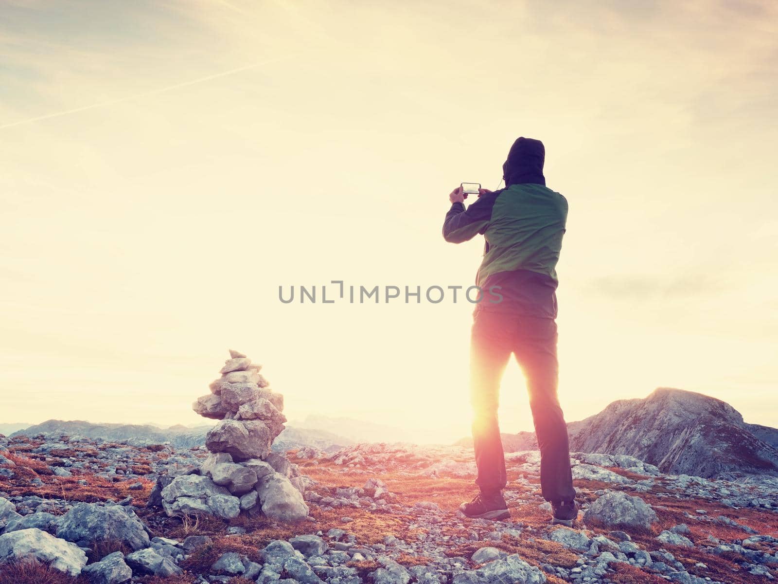 Tourist in green jacket at pebbles pyramid on sharp Alps view point. National Alps park by rdonar2