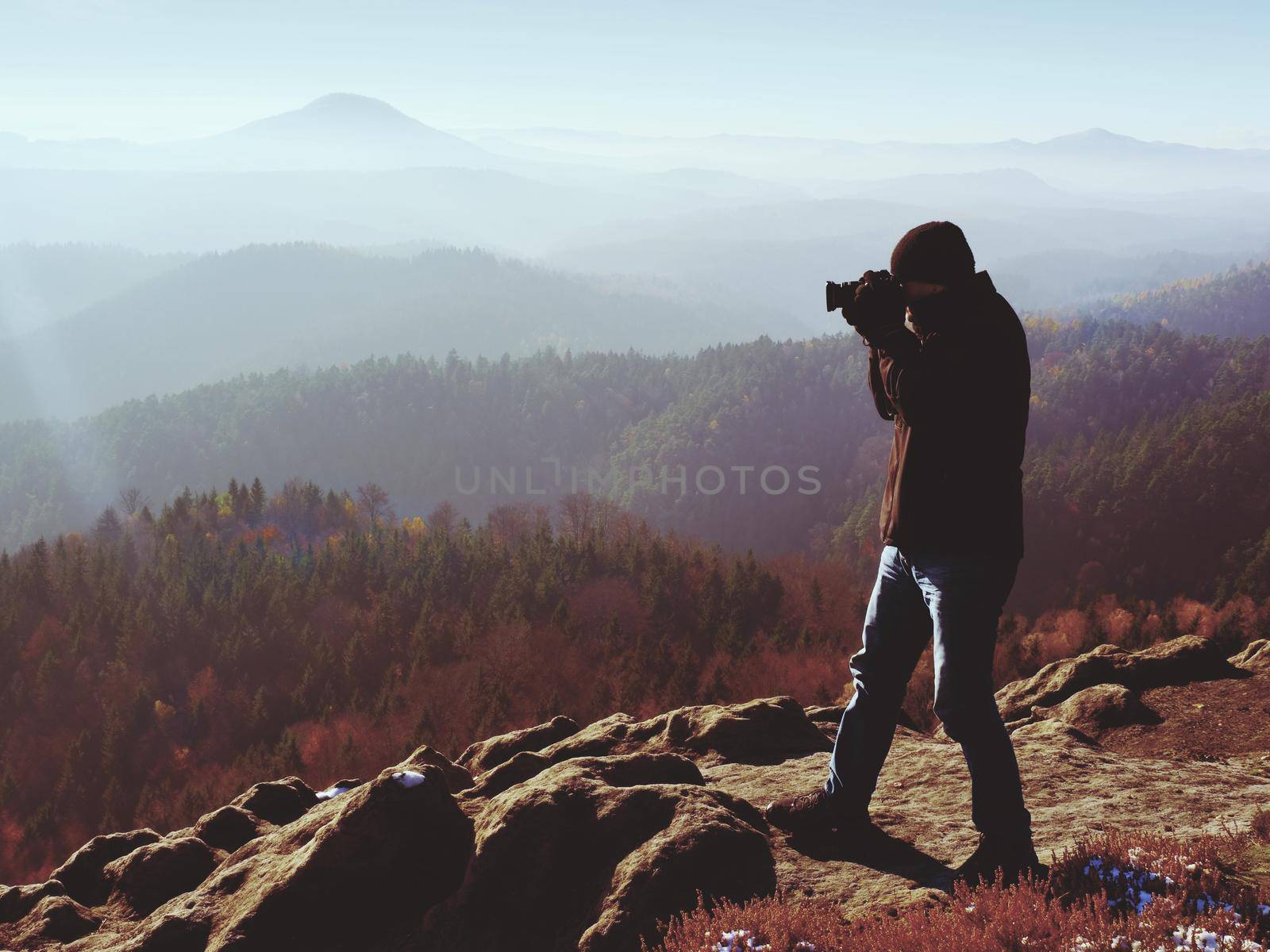 Professional photographer takes photos with mirror camera on peak of rock. Dreamy fog by rdonar2
