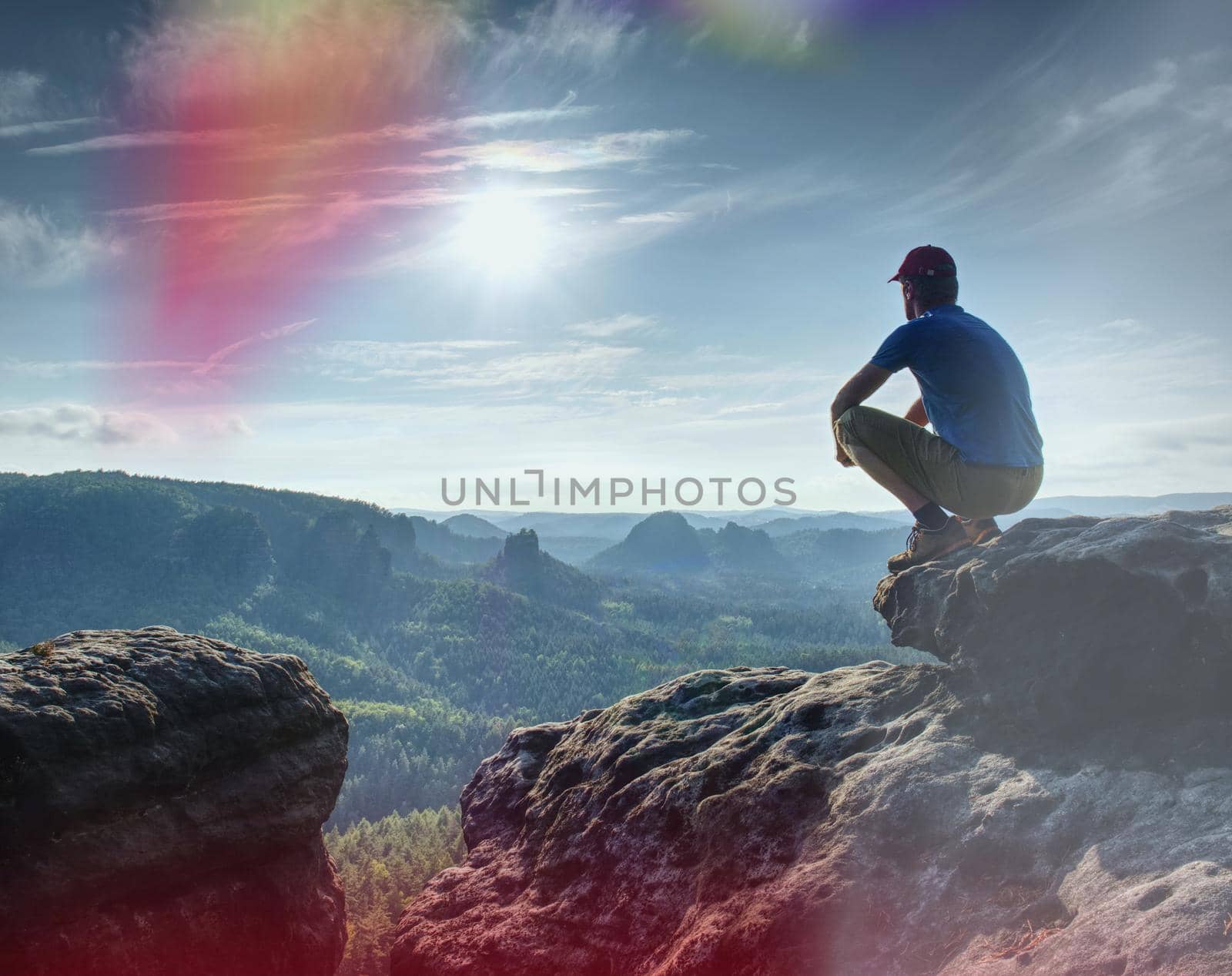 Man sitting on the rock cliff in mountain and watching on sunrise landscape. Nature composition.