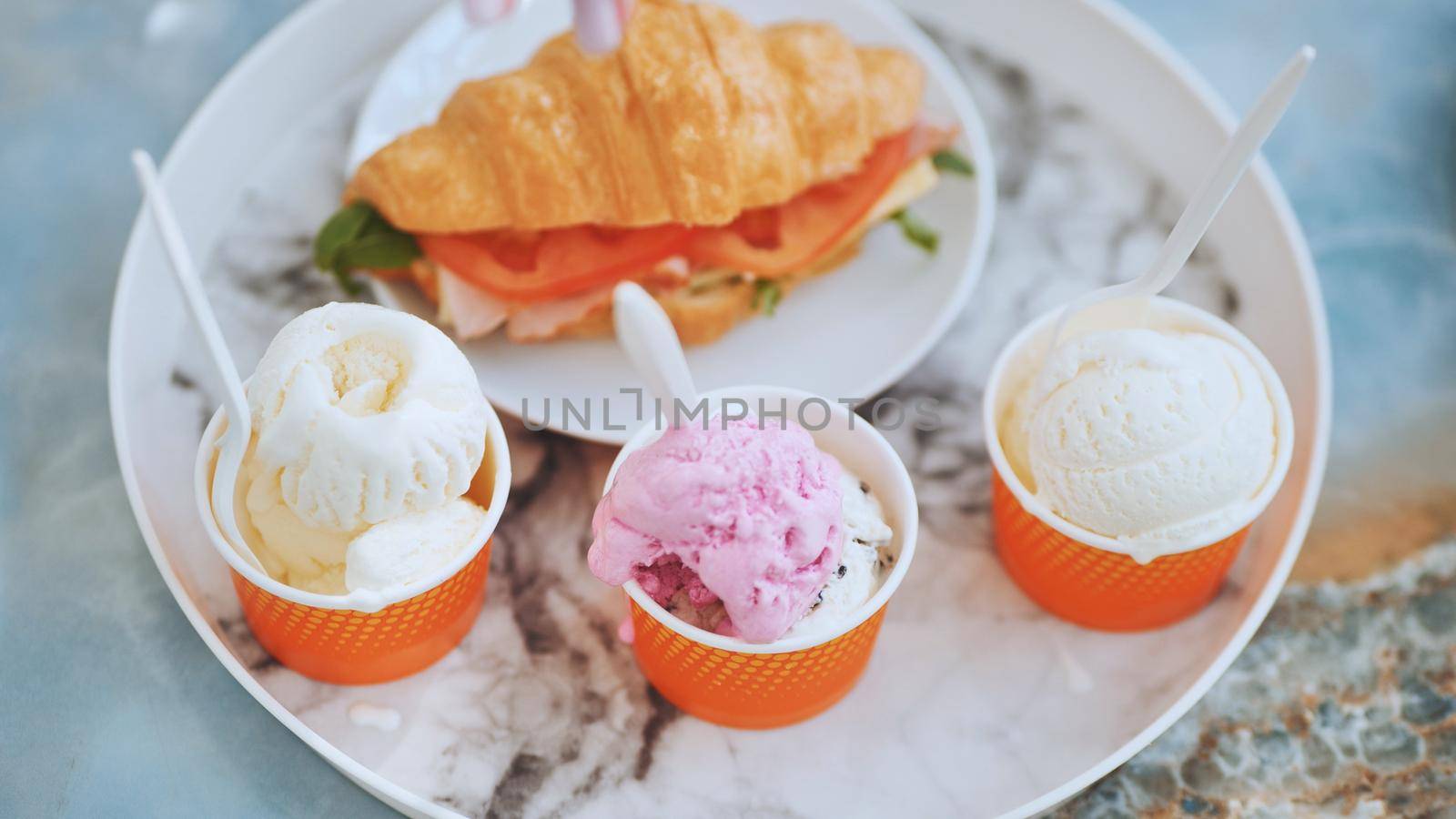 Ice cream and croissant with meat on the plate at the cafe