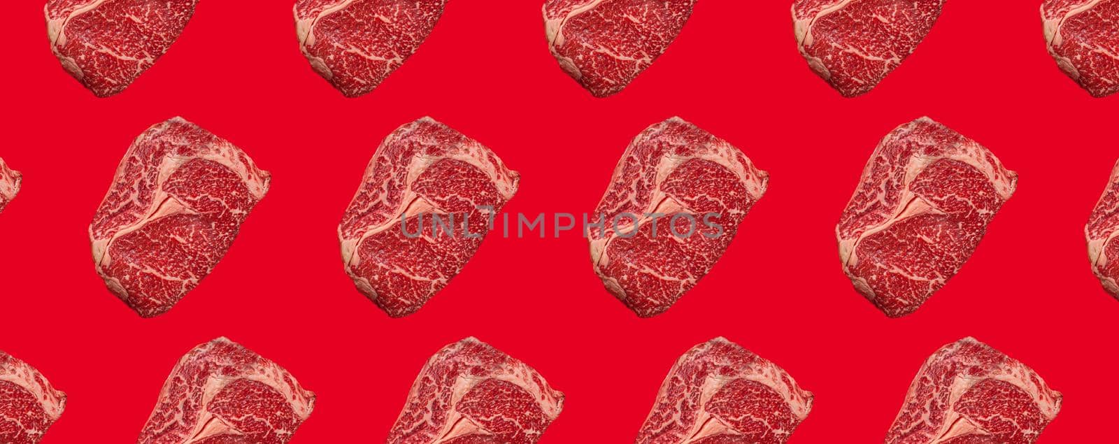Pattern made of raw meat beef marbled prime cut steak Ribeye on red clean background from above, minimalist beefsteak concept
