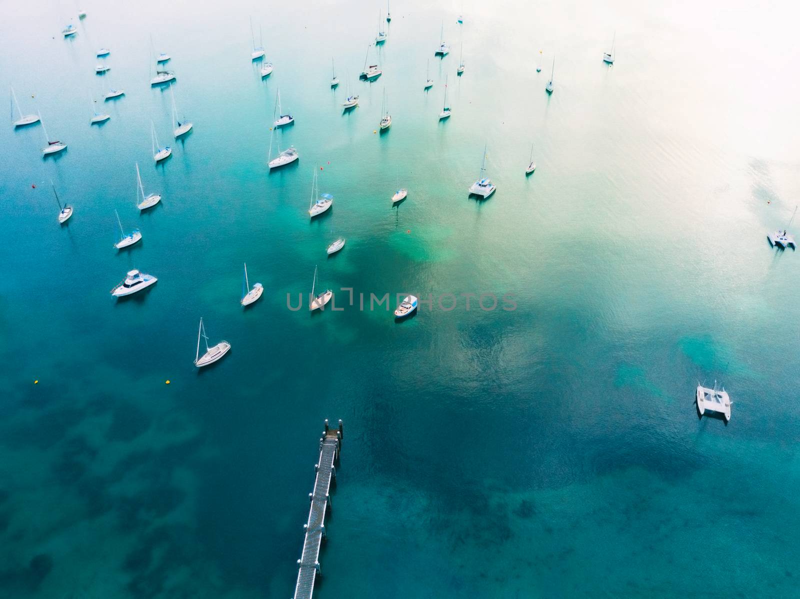 Aerial views of yachts and boats in the bay,  with morning light reflections