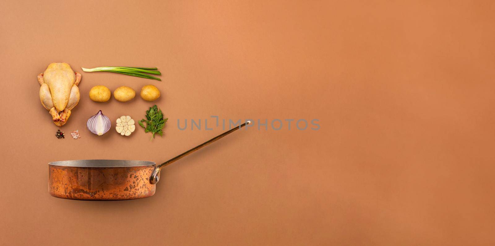 Set of raw ingredients arranged for cooking chicken soup or stew in copper pot: chicken, potatoes, vegetables on brown background from above. Healthy meal with poultry for dinner, space for text
