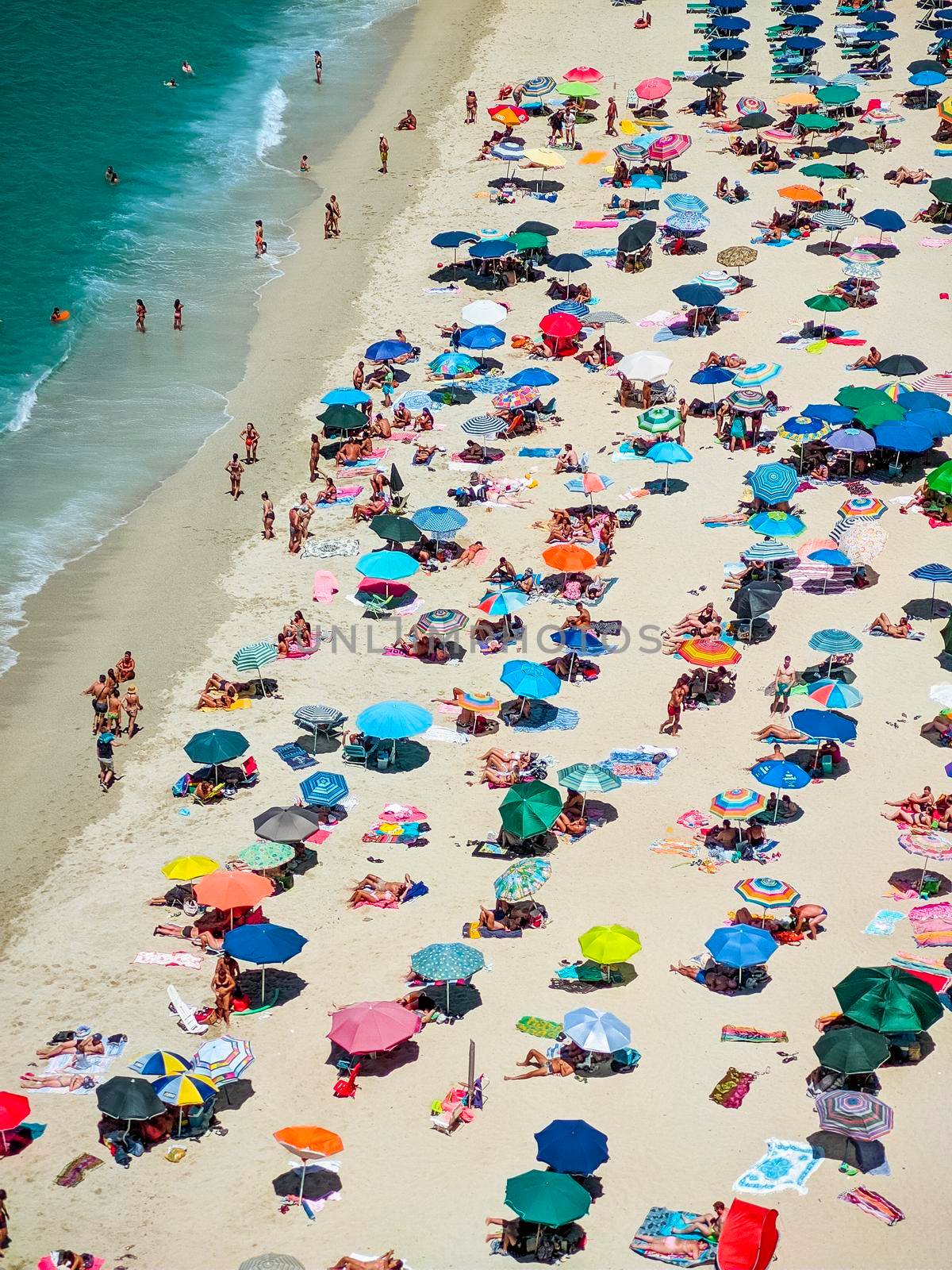 Italian beaches of Calabria seen from above, tourists seen rest under colorful umbrellas, travel reportage in Tropea Town