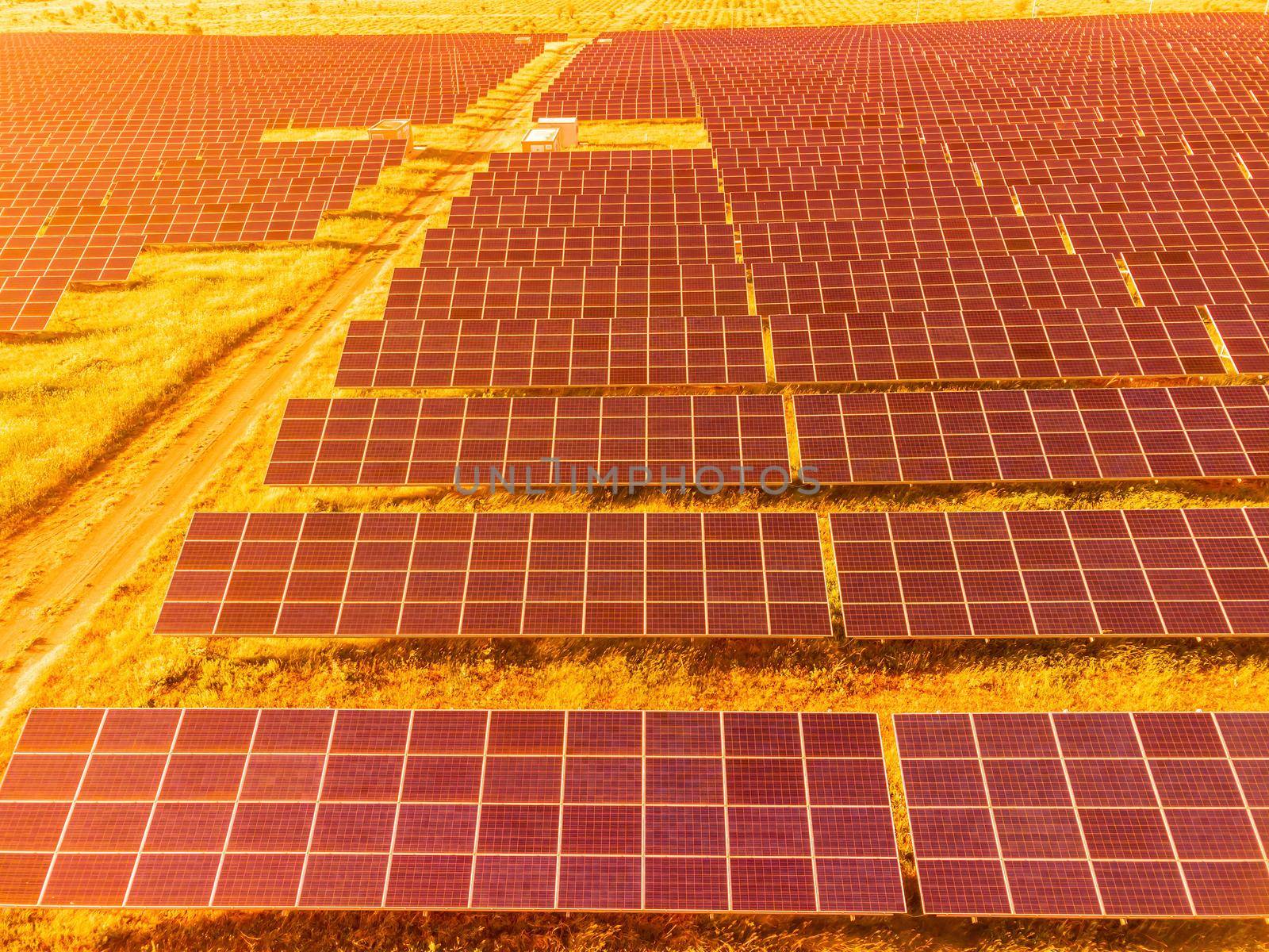 Aerial top view of a solar panels power plant. Photovoltaic solar panels at sunrise and sunset in countryside from above. Modern technology, climate care, earth saving, renewable energy concept