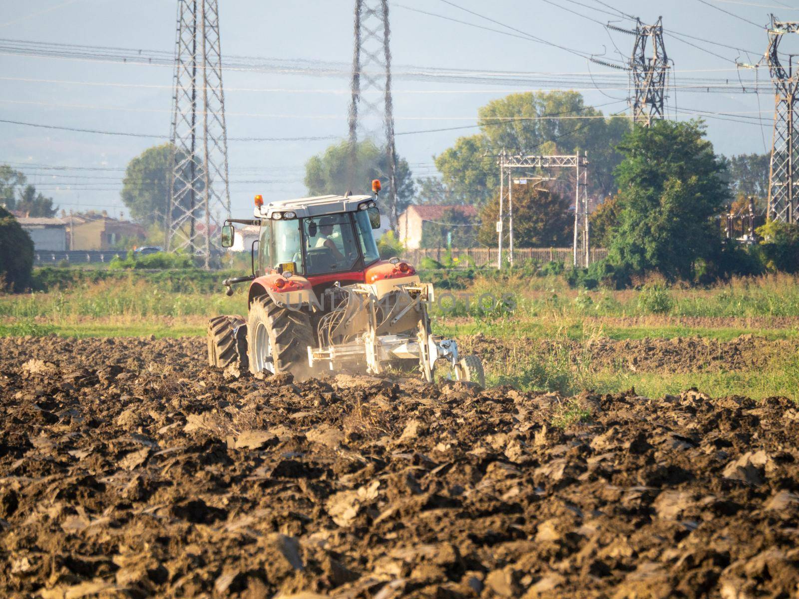 Farmer driving tractor plowing land at the end of the summer season by verbano