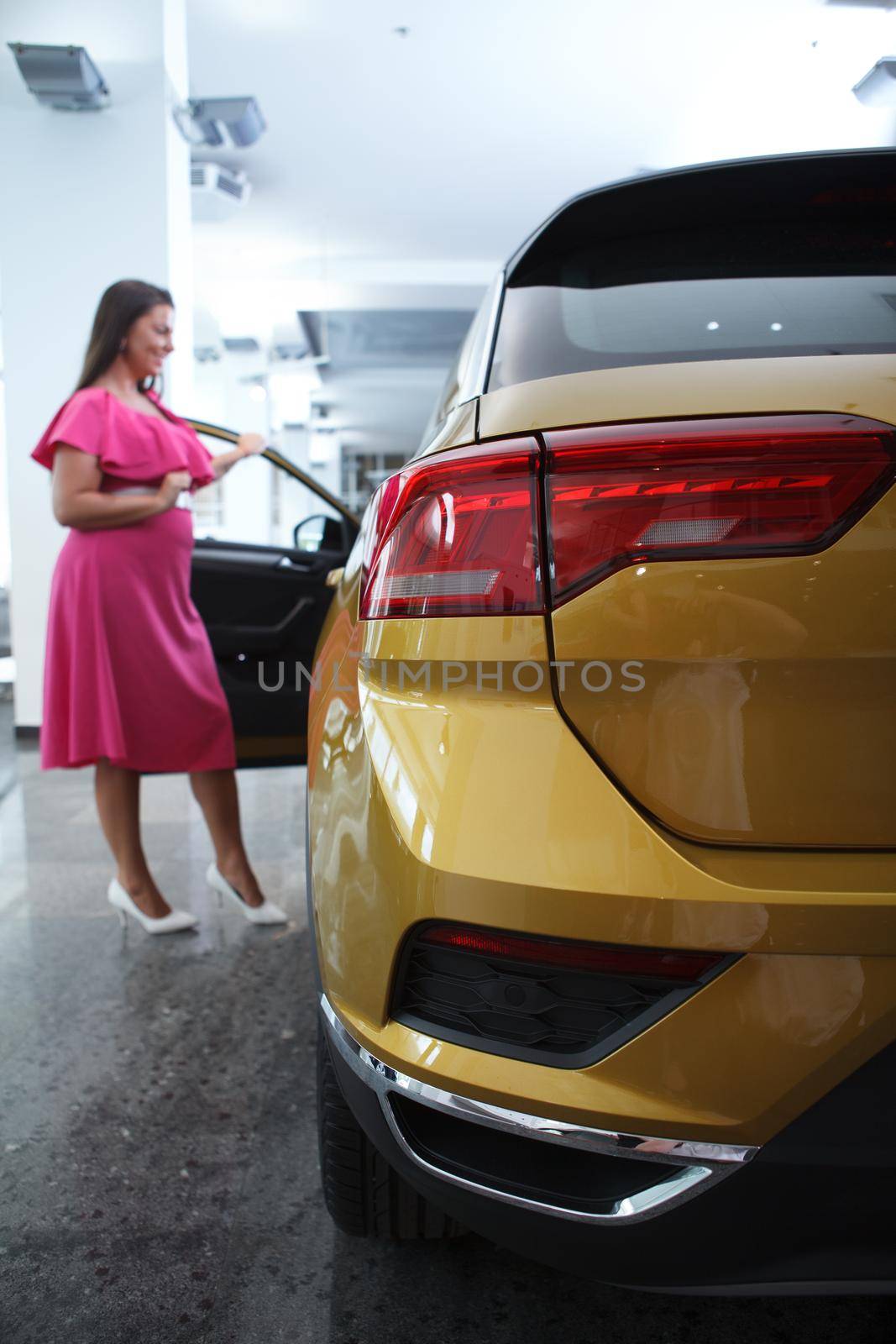 Selective focus on a car female customer choosing auto to buy at dealership on background
