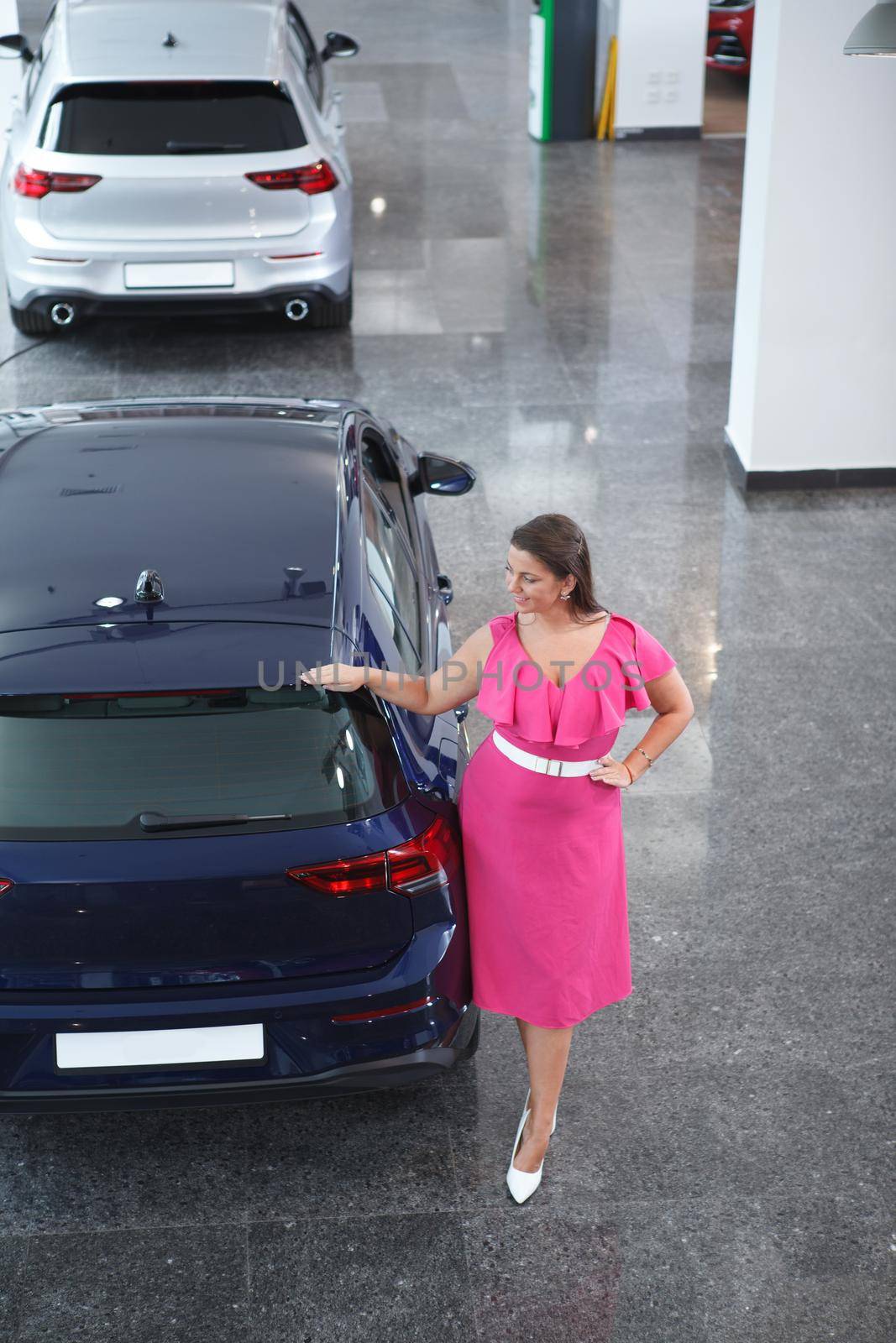Top view full length shot of a cheerful plus size woman choosing new auto to buy at the dealership