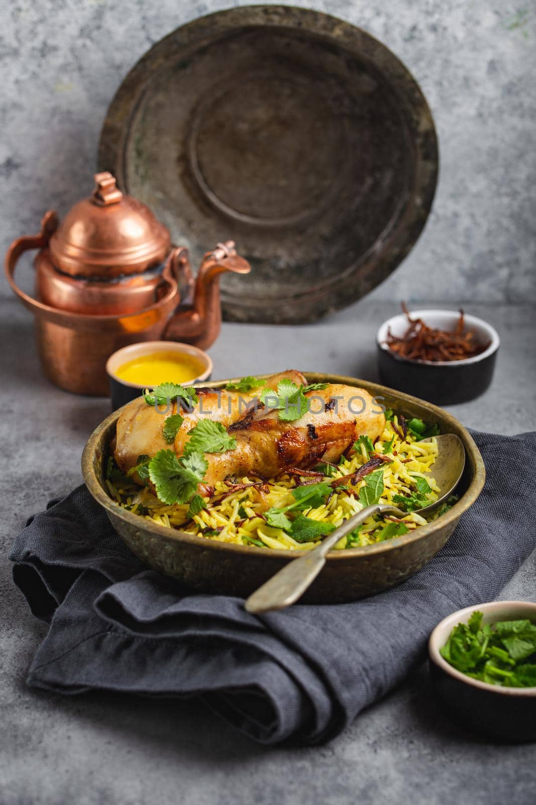 Biryani chicken, traditional dish of Indian cuisine, with basmati rice, fried onion, fresh cilantro in bowl on gray rustic stone background. Authentic Indian meal, close-up, selective focus