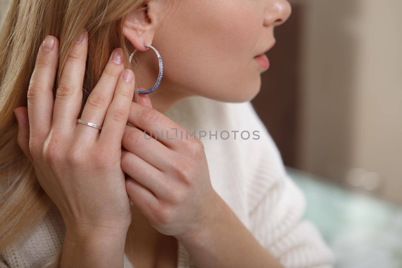 Cropped close up of a female trying on diamond earrings at jewelry shop