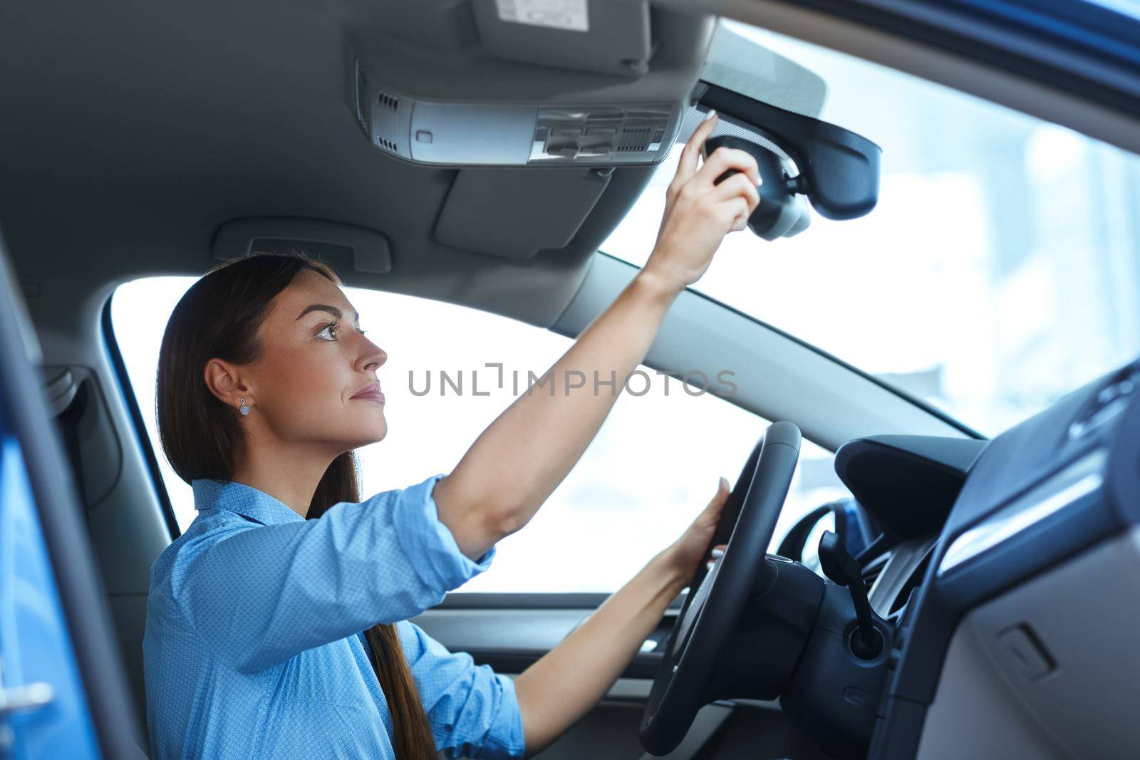 Mirrors fixed. Low angle shot of an attractive woman adjusting a mirror while sitting in a car