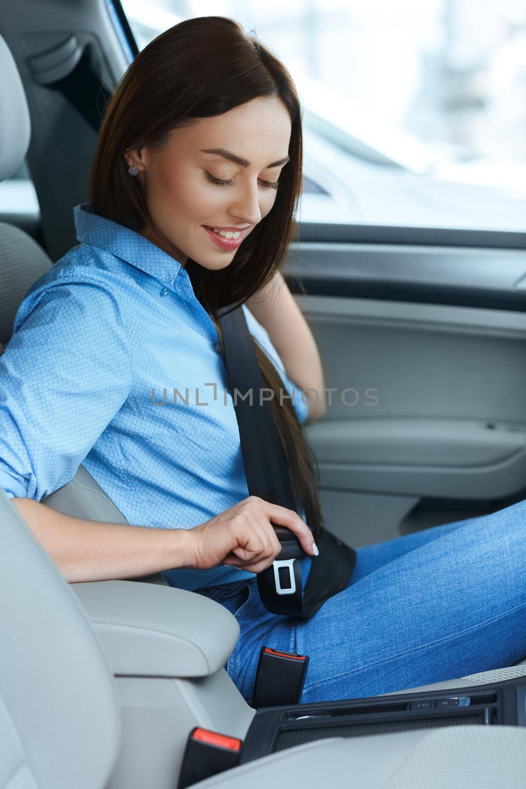 Safety on point. Vertical Shot of a beautiful woman sitting in a car putting her seatbelt on smiling joyfully