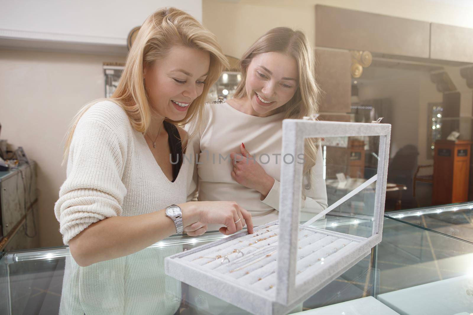 Cheerful female friends enjoying shopping for jewelry together