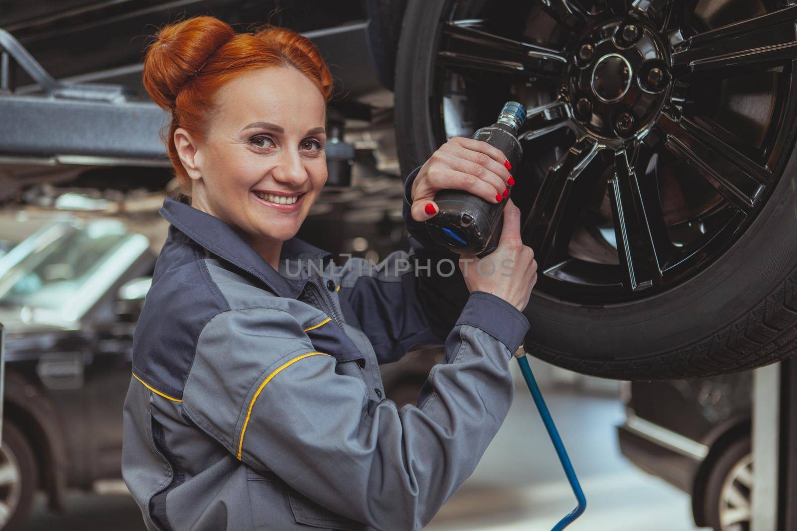 Female mechanic working at car service station by MAD_Production