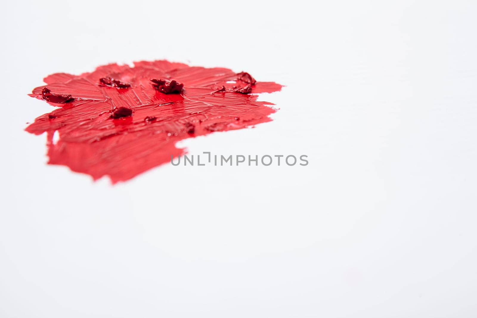 Red lipstick smudged on white background, copy space