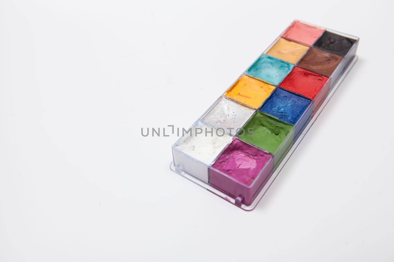 Colorful cream face paint in a palette isolated on white