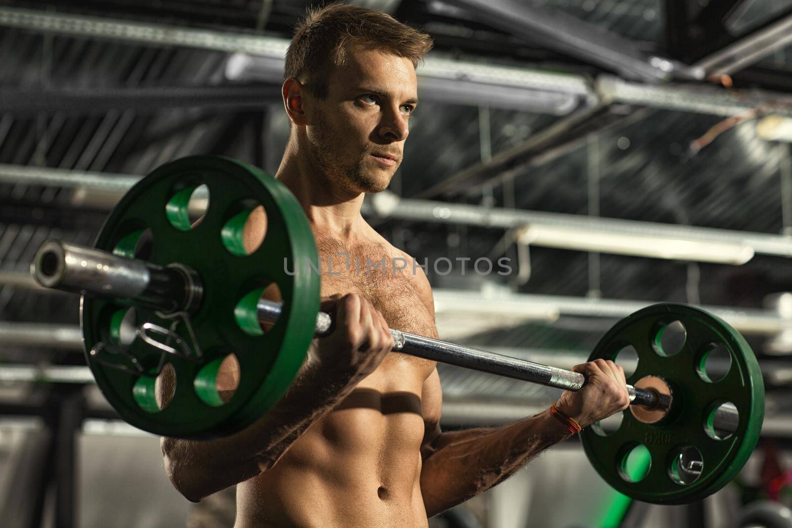 Workout set. Low angle shot of a strong confident handsome man looking focused while exercising with a barbell at the gym motivation sports challenge competitive muscles fitness health concept