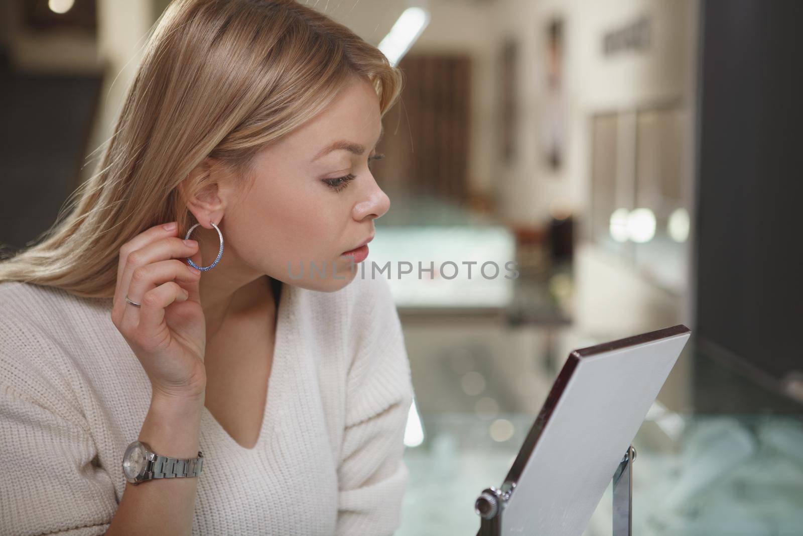 Close up of a gorgeous woman trying on diamond earrings at jewelry store