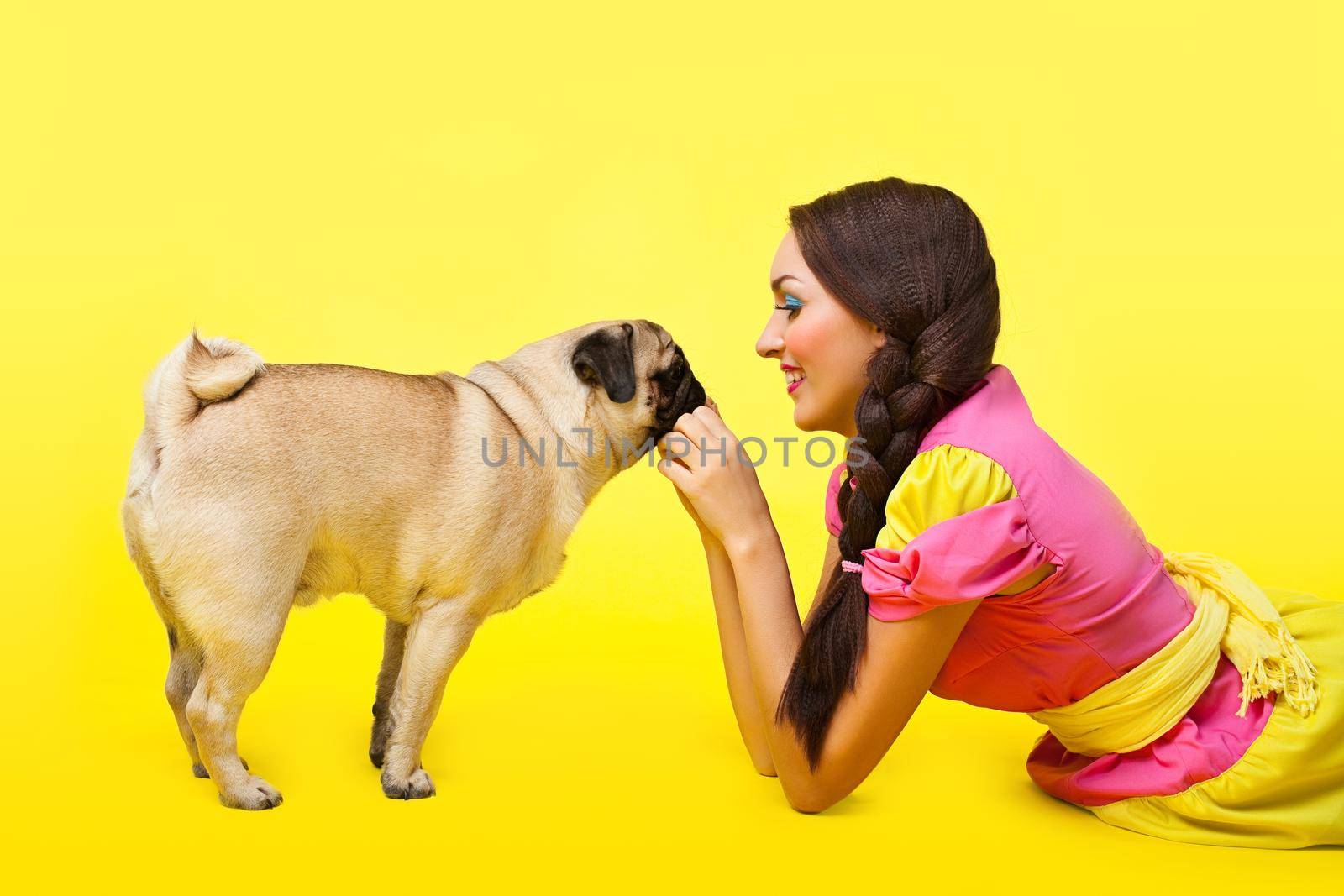 Happy girl like cute doll feed a small dog on yellow background