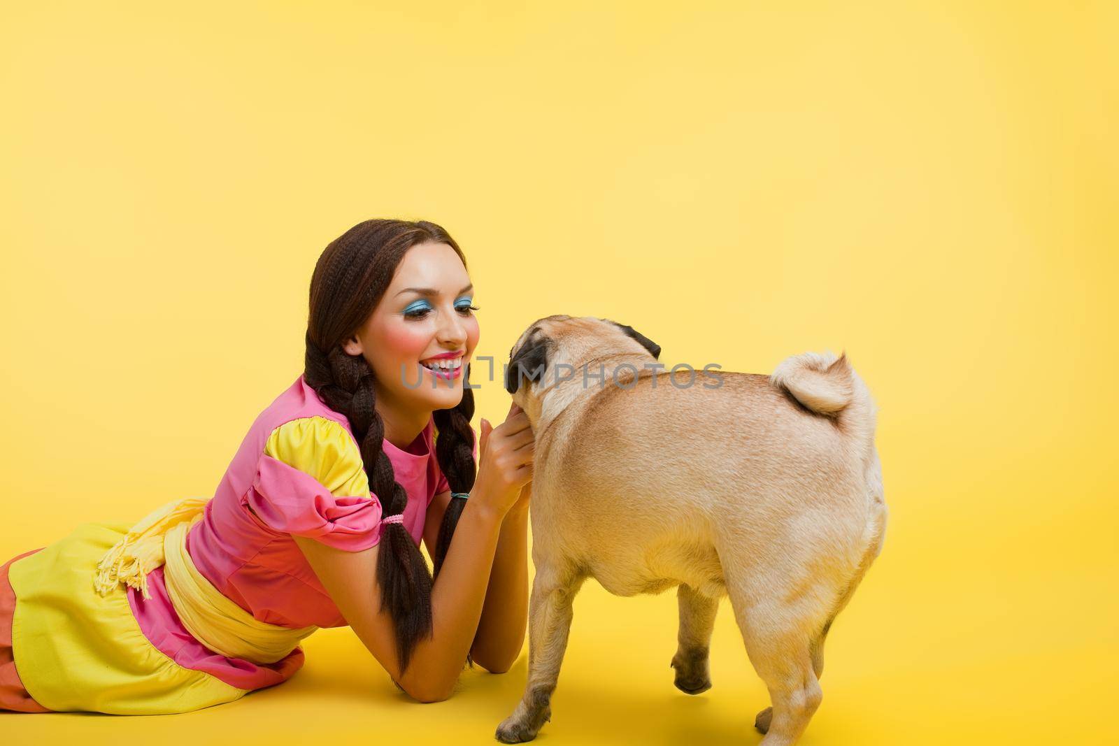 Happy girl like cute doll feed a small dog on yellow background