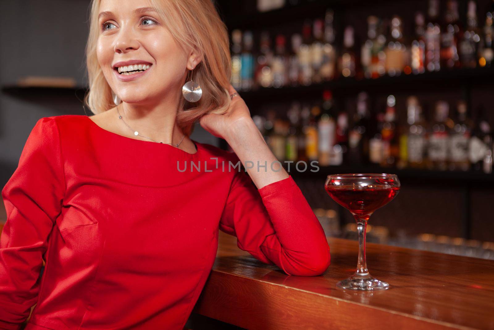 Cropped shot of a charming beautiful woman smiling, looking away, resting at the bar. Attractive woman relaxing at the bar after work