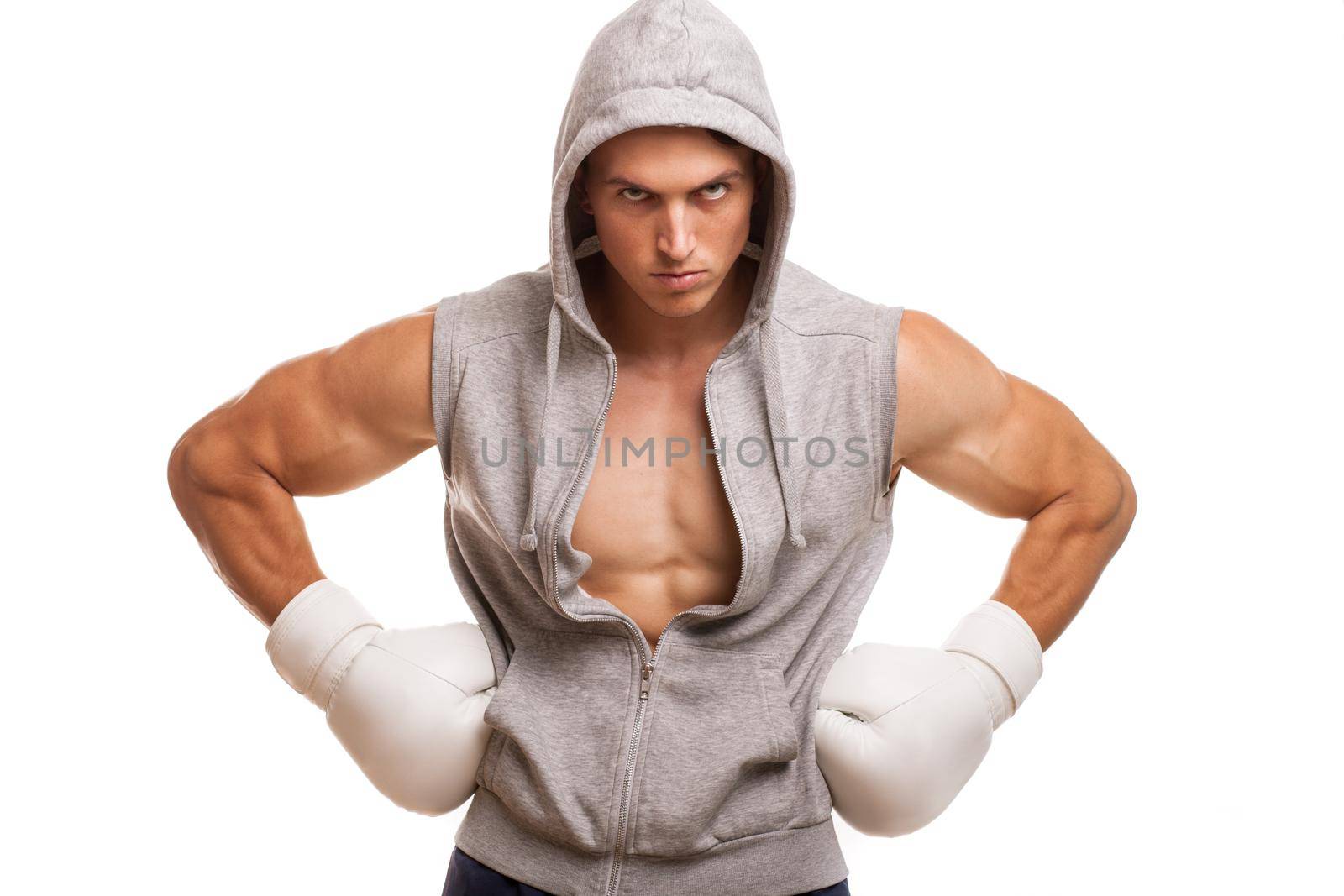 Handsome ripped male athlete wearing boxing gloves looking angrily. Aggressive boxing fighter with muscular body isolated. Muay thai boxer wearing hoodie. Health, sport, motivation concept