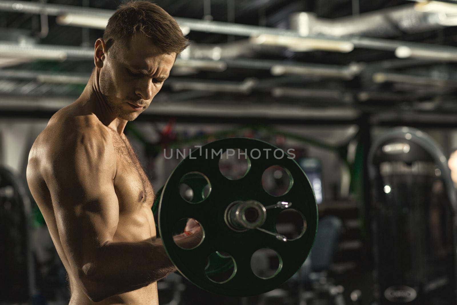 Training routine. Profile shot of a handsome shirtless muscular man with sexy fit and toned body doing biceps exercise using barbell at the gym copyspace fitness lifestyle masculinity activity concept