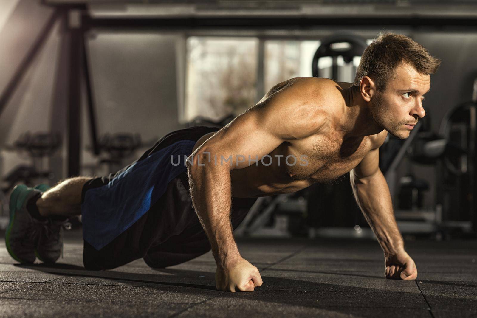 Pushing his limits. Full length shot of a shirtless man with toned muscular athletic body doing pushups working out at the gym confidence agility strength competition sports training concept