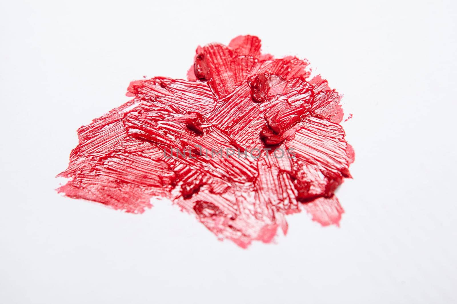 Close up of crushed and smudged red lipstick swatch on white background