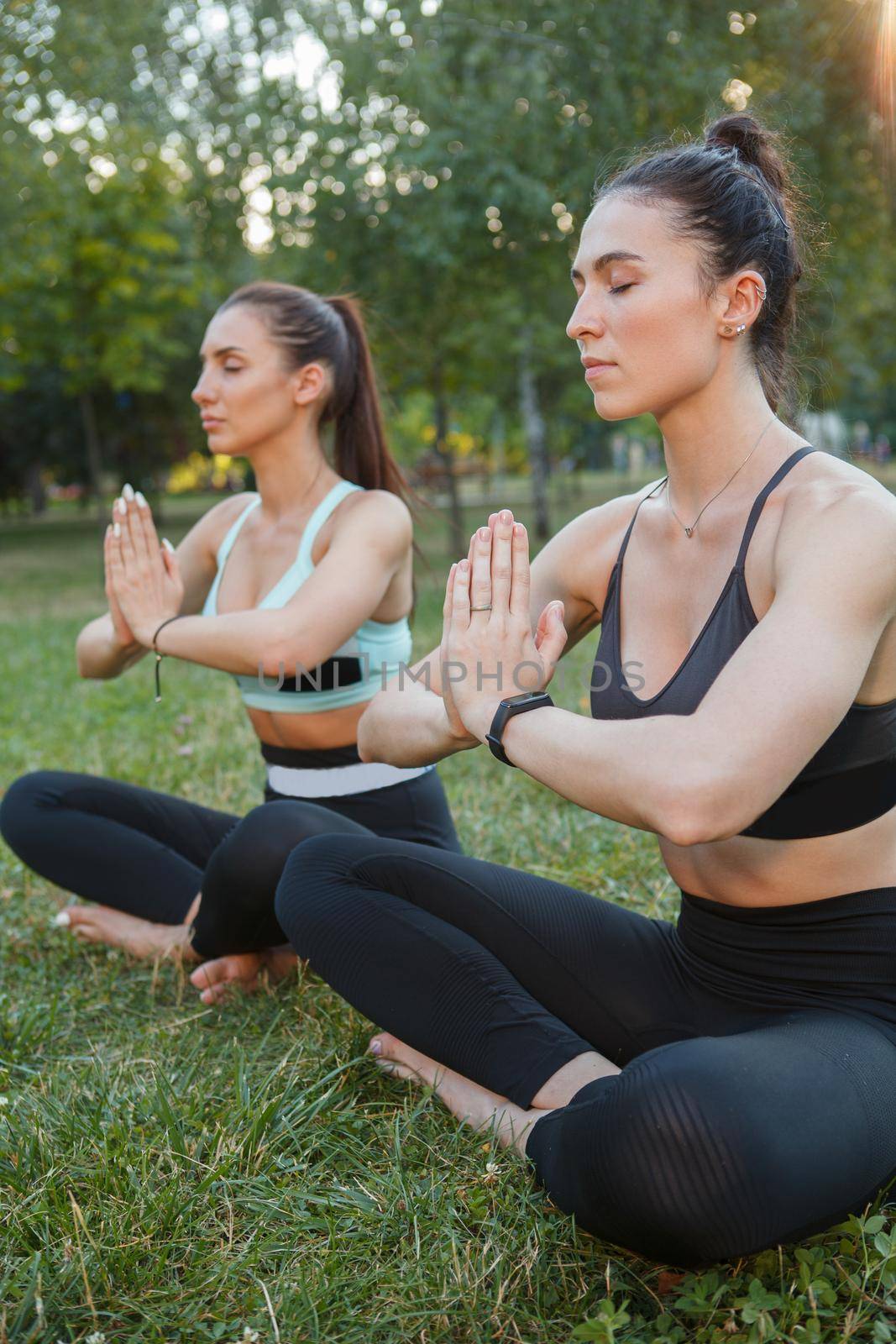 Women doing yoga outdoors at the park by MAD_Production