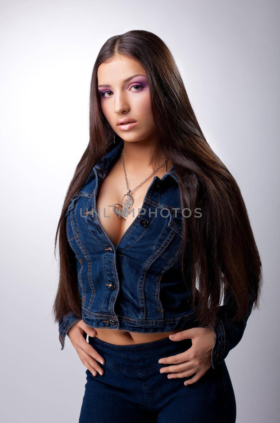 Sexy young brunette portrait posing in jeans costume with long hair