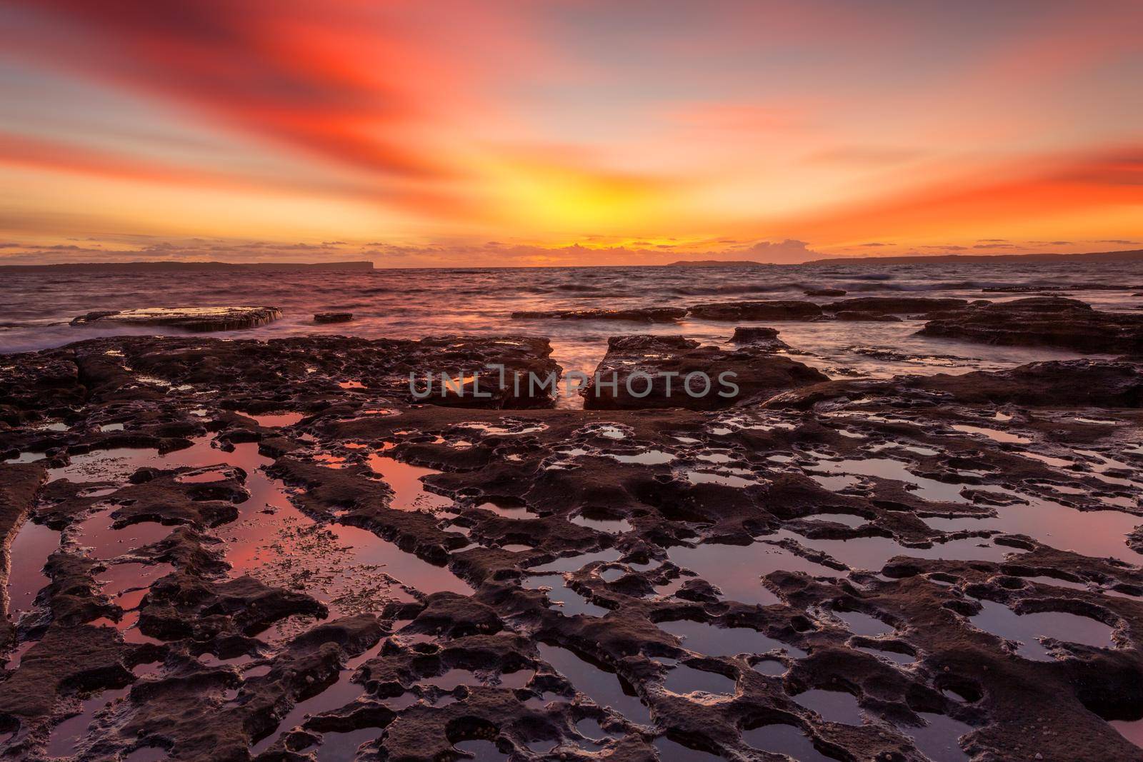 Rich red sunrise at Plantation Point, Jervis Bay, Australia with reflections in the tidal waters