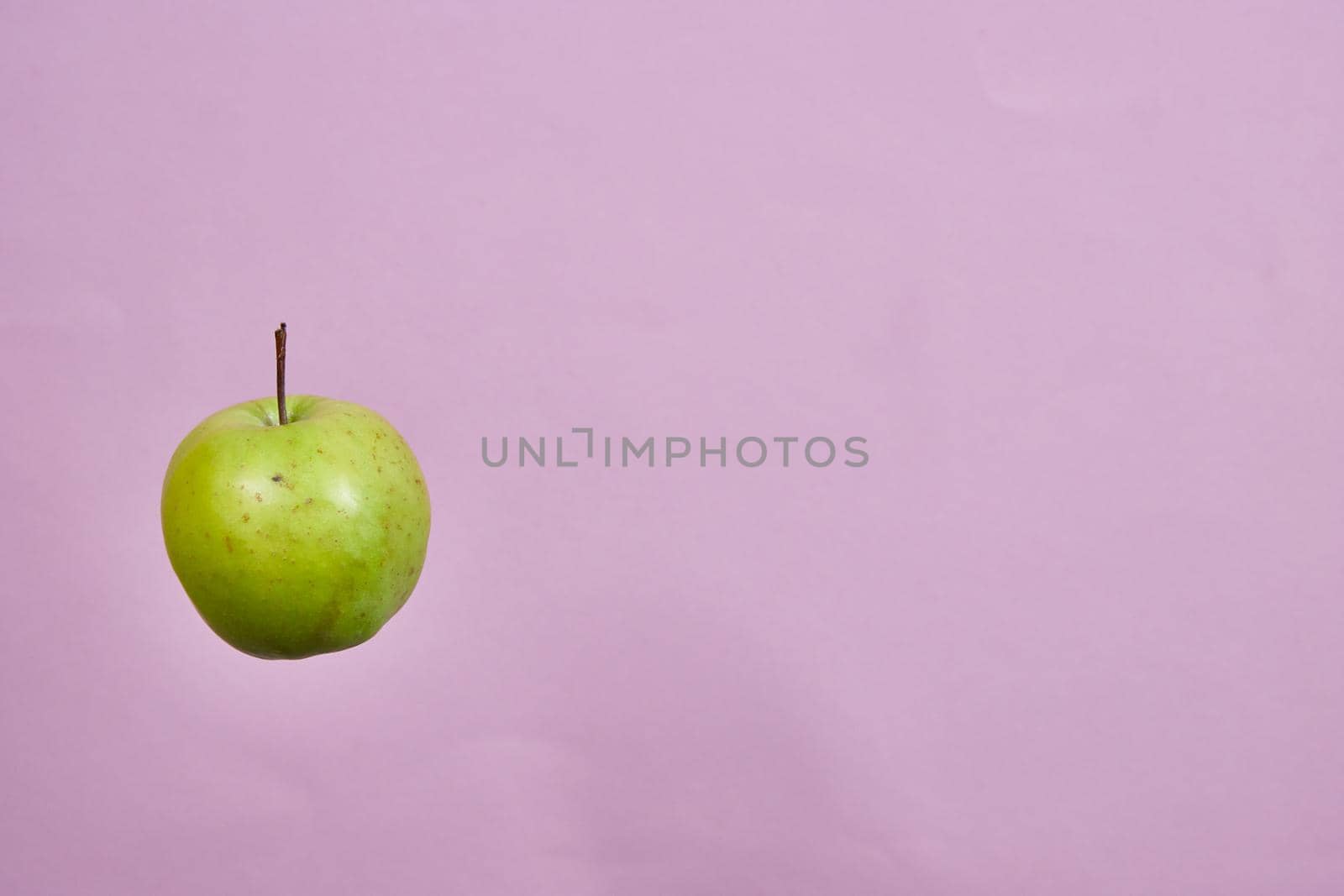 three green apples spinning on a pink background.