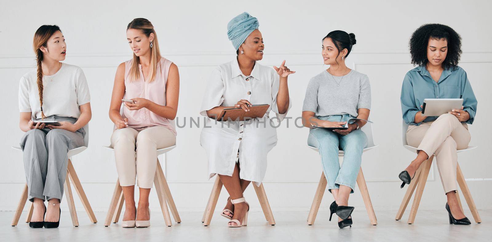 Hiring, recruitment and interview of business women waiting for company management hire team. Diversity of talking and work communication of group using technology in a office to wait for a meeting by YuriArcurs