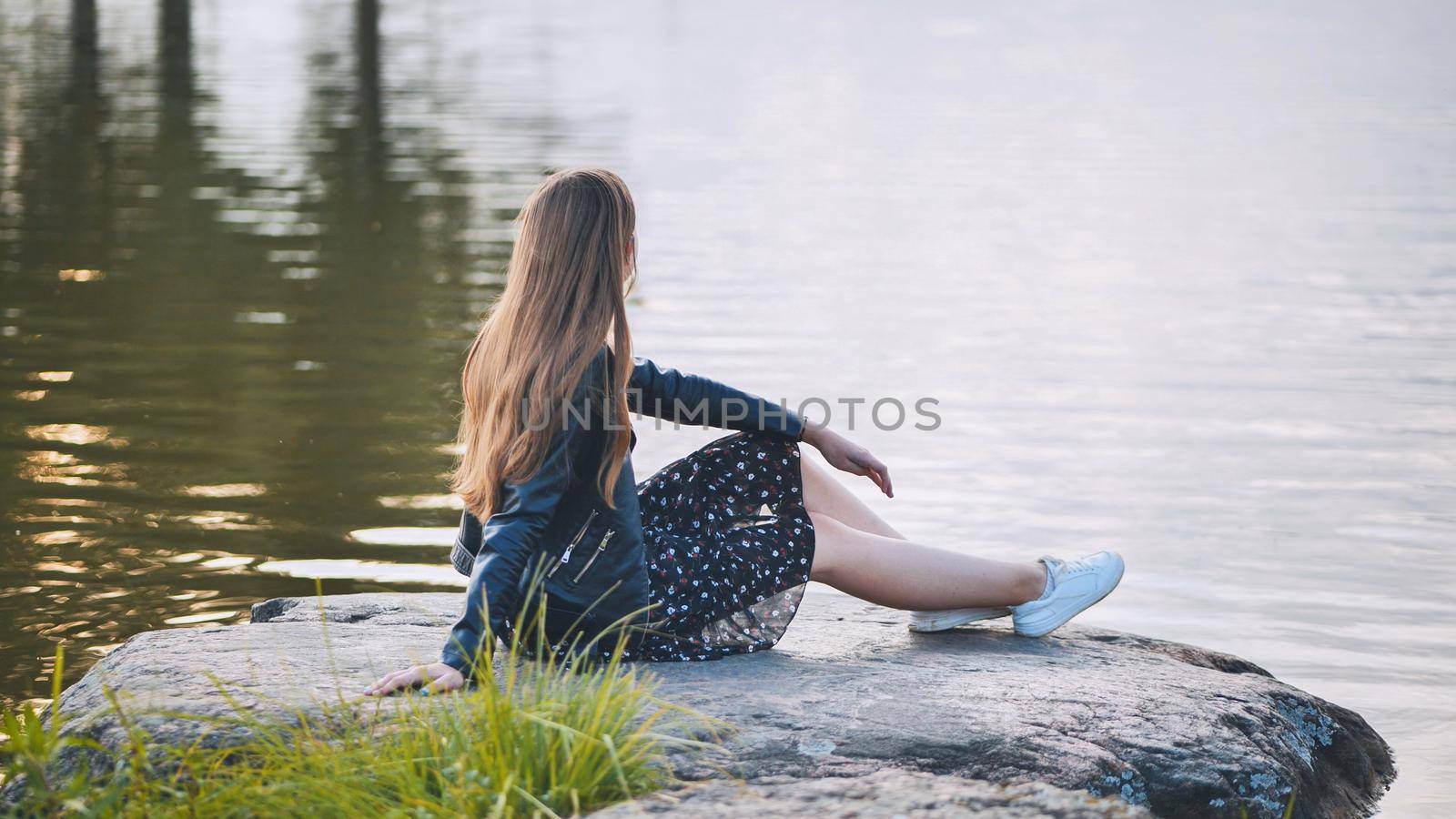 A girl sits by the lake on a rock