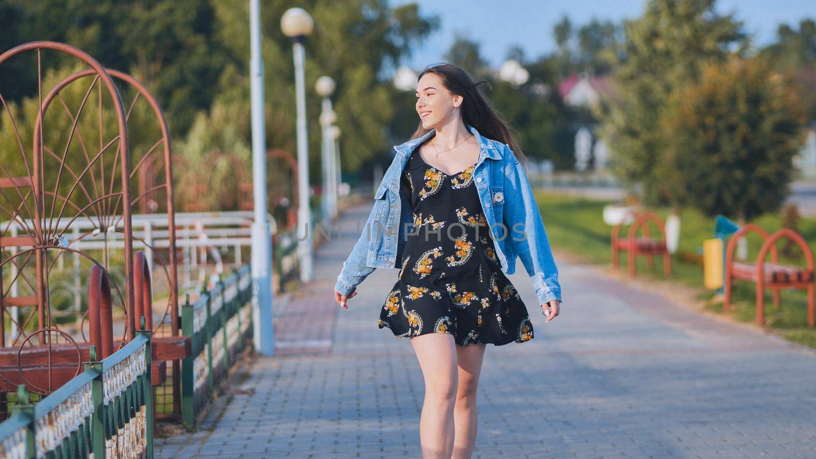 A cheerful girl walks along the city promenade