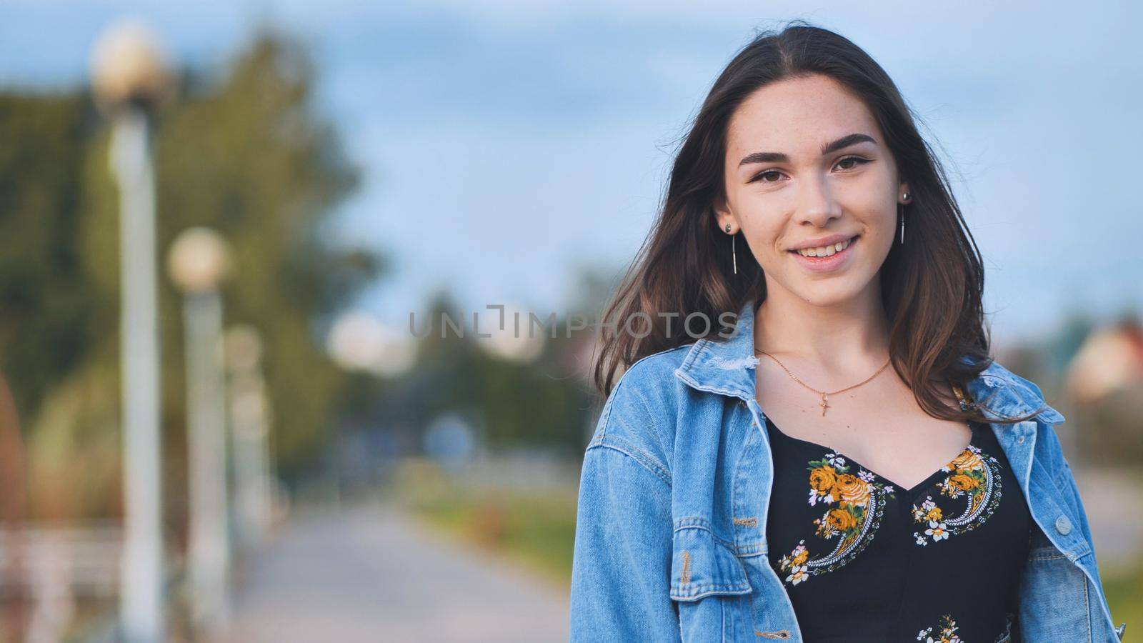 Portrait of a cheerful girl in a denim jacket at night in the city