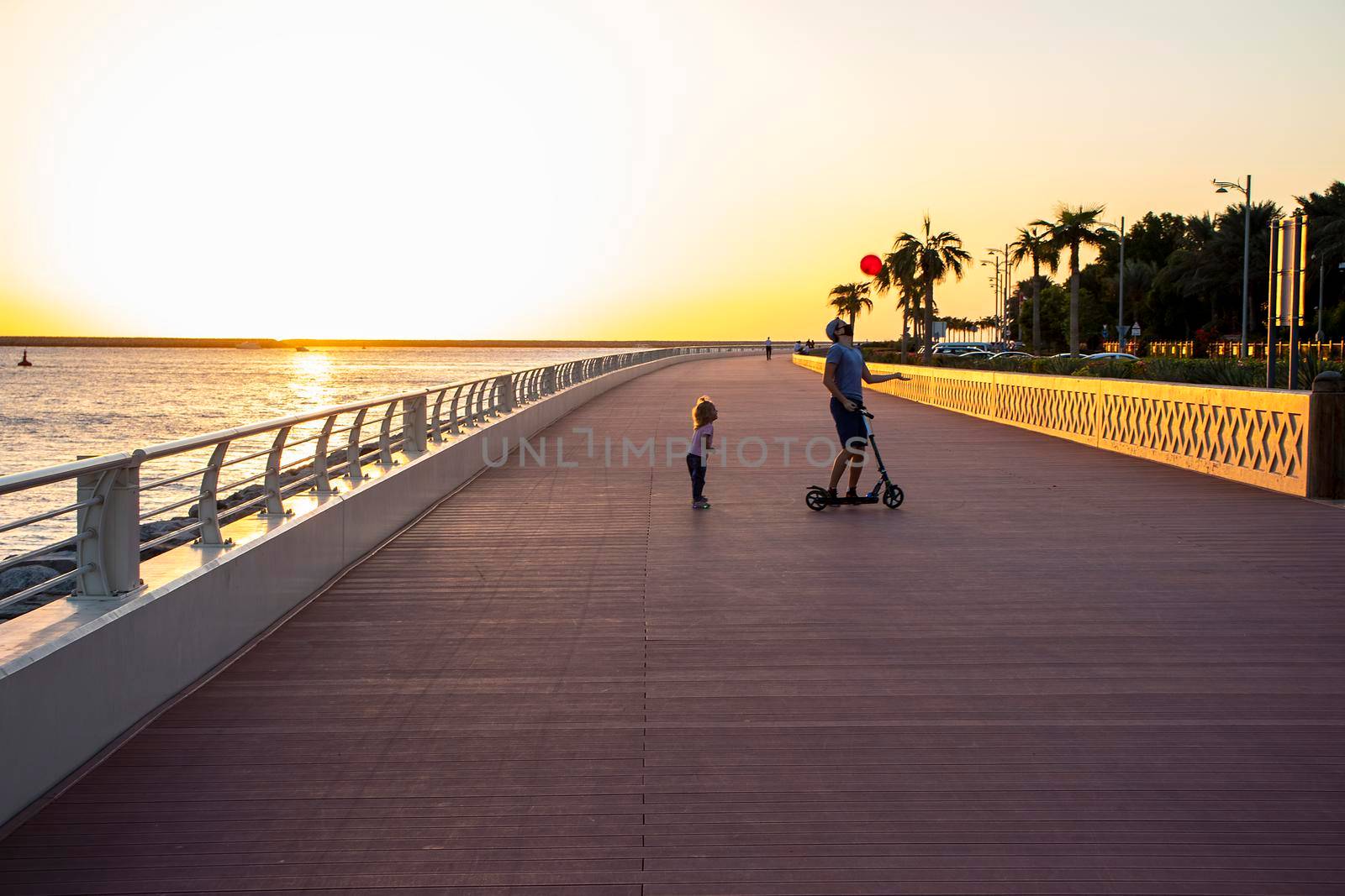 Children playing with balloon on boardwalk during sunset hour. Outdoors.