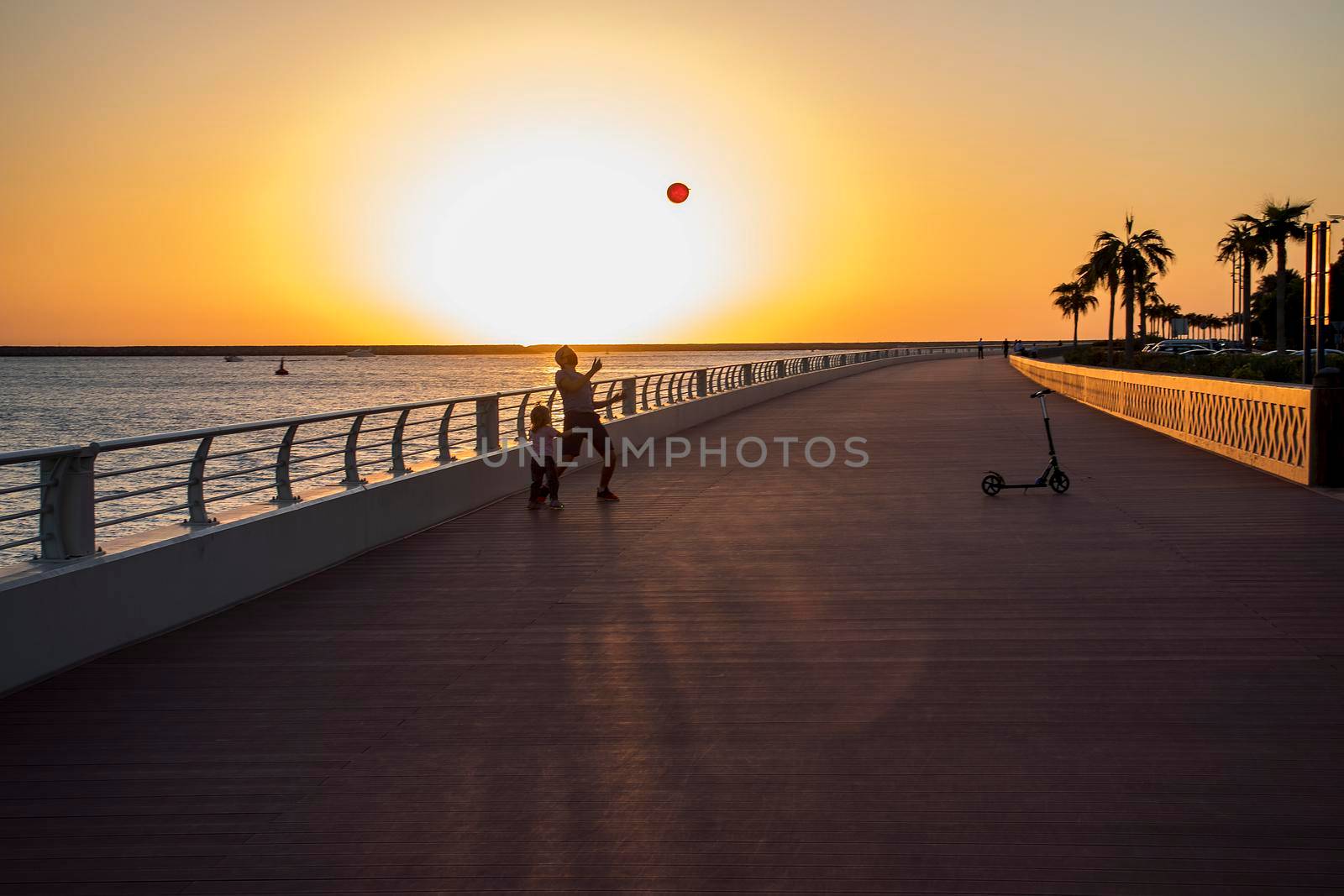 Children playing with balloon on boardwalk during sunset hour. Outdoors.