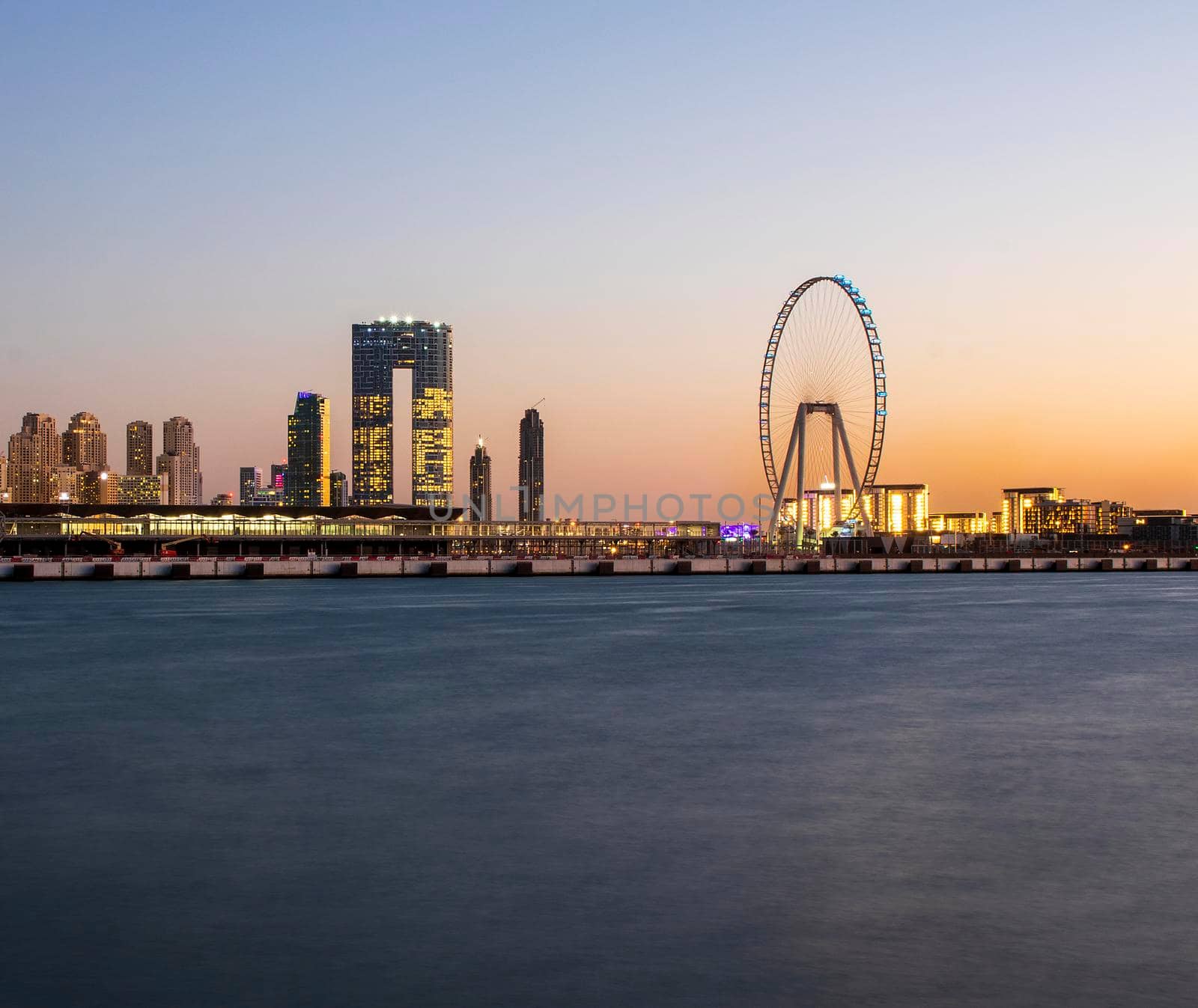 View of A Jumeirah Beach Residence and Blue watersafter sunset. Shot made from Palm Jumeirah, man made island. Tallest ferris wheel, Ain Dubai can also be seen in the scene Dubai, UAE. by pazemin