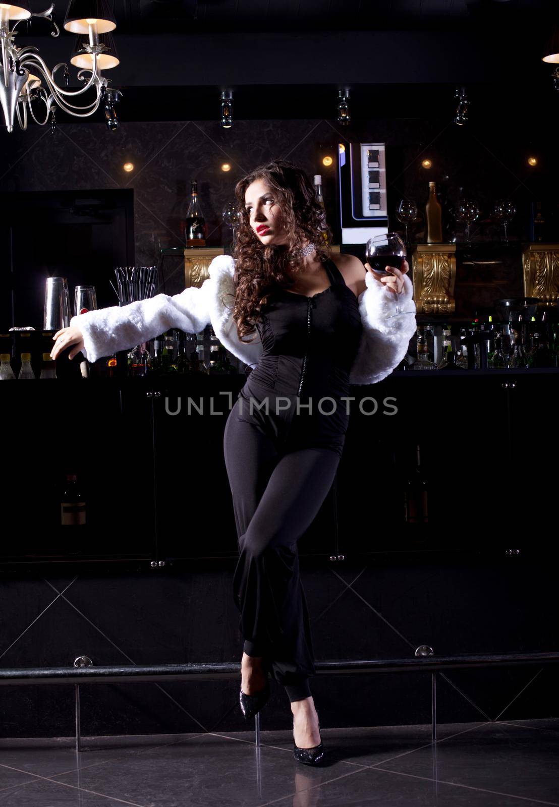 Beauty woman stand near bar in luxury cloth and white fur coat