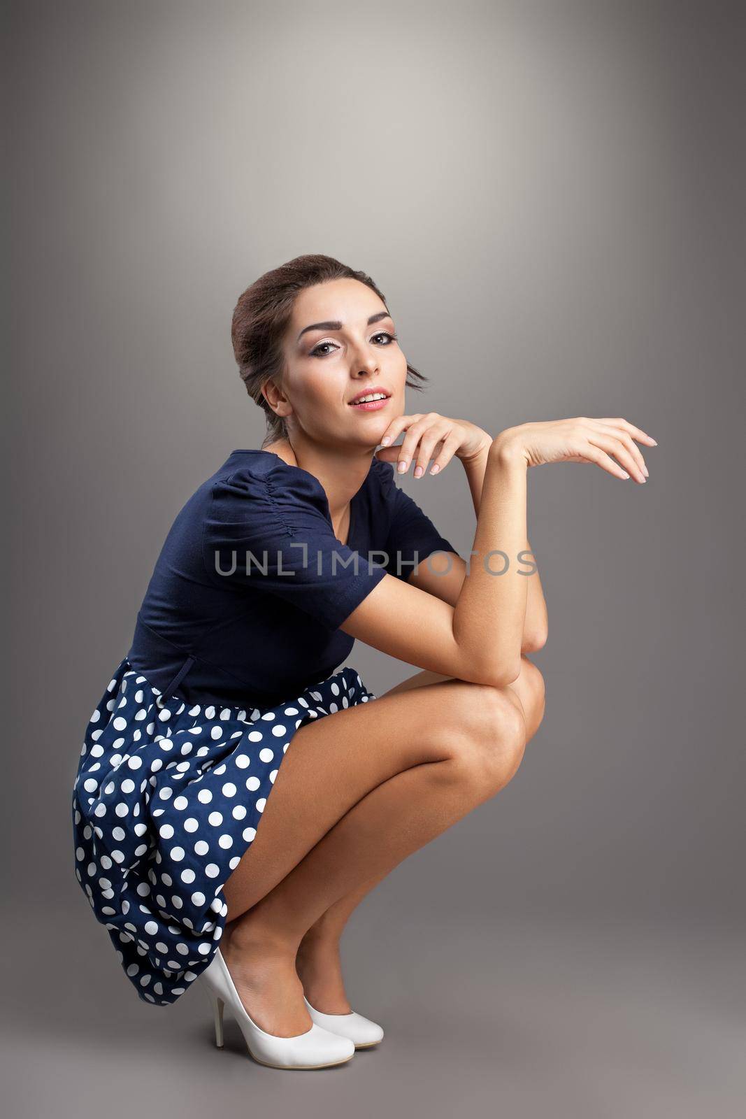 Beautiful young woman in retro style dress sit and look at camera