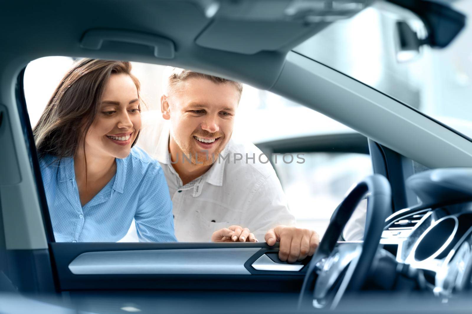 Happy couple examining interior of a new car at the dealership