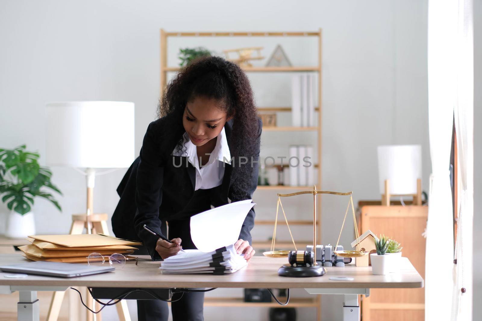 Attractive young lawyer in office Business woman and lawyers discussing contract papers with brass scale on wooden desk in office. Law, legal services, advice, Justice and real estate concept. by wichayada