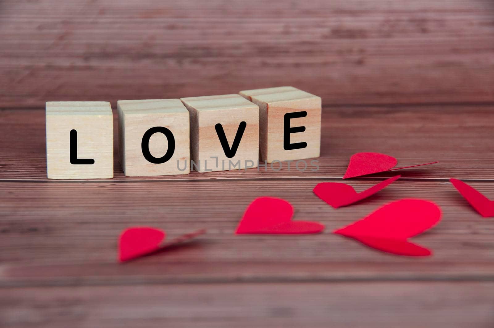 Love text on wooden blocks with heart shape and wooden background. Romance and relationship concept.