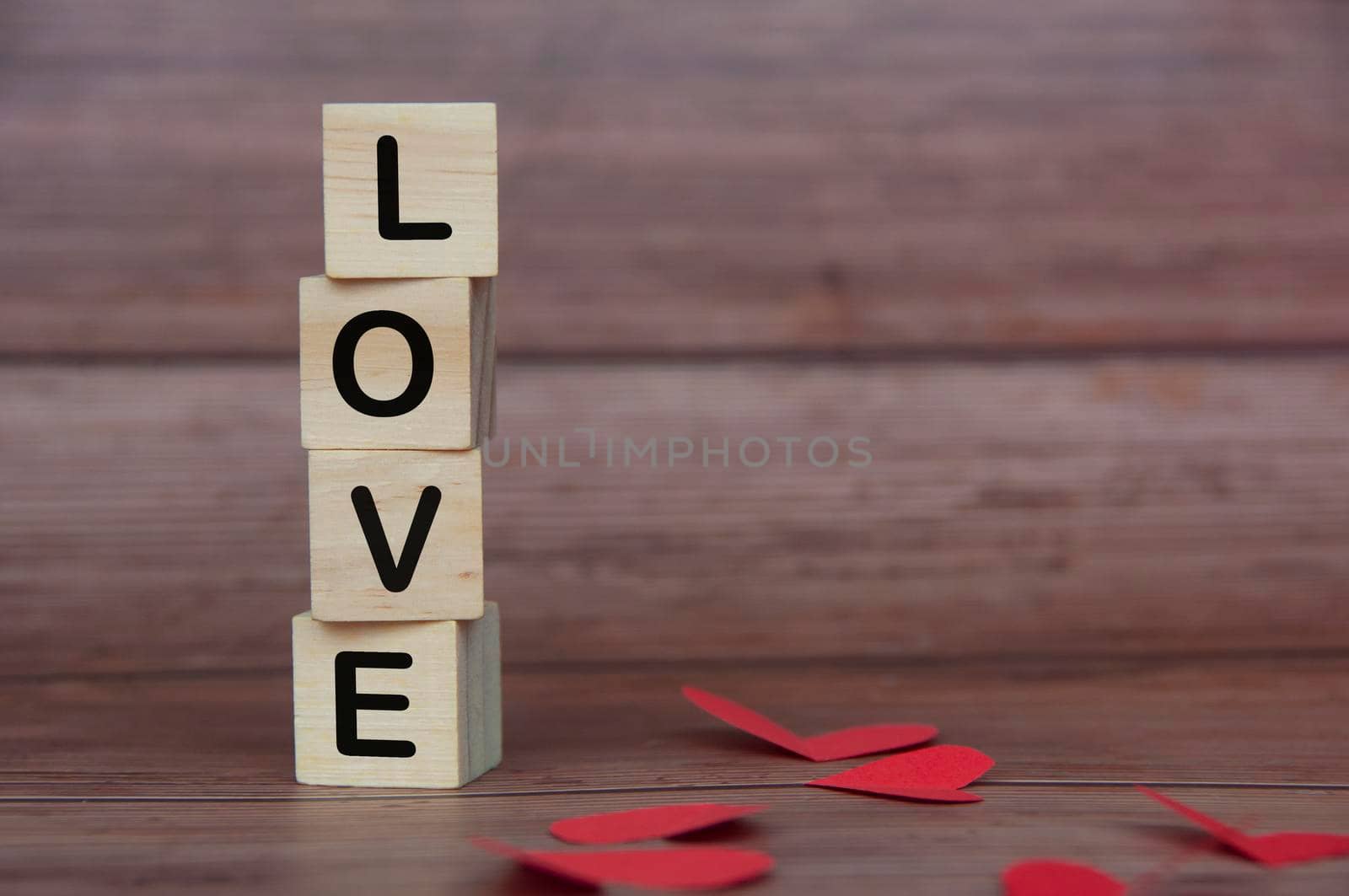 Love text on piled up wooden blocks with heart shape and wooden background. Romance and relationship concept.